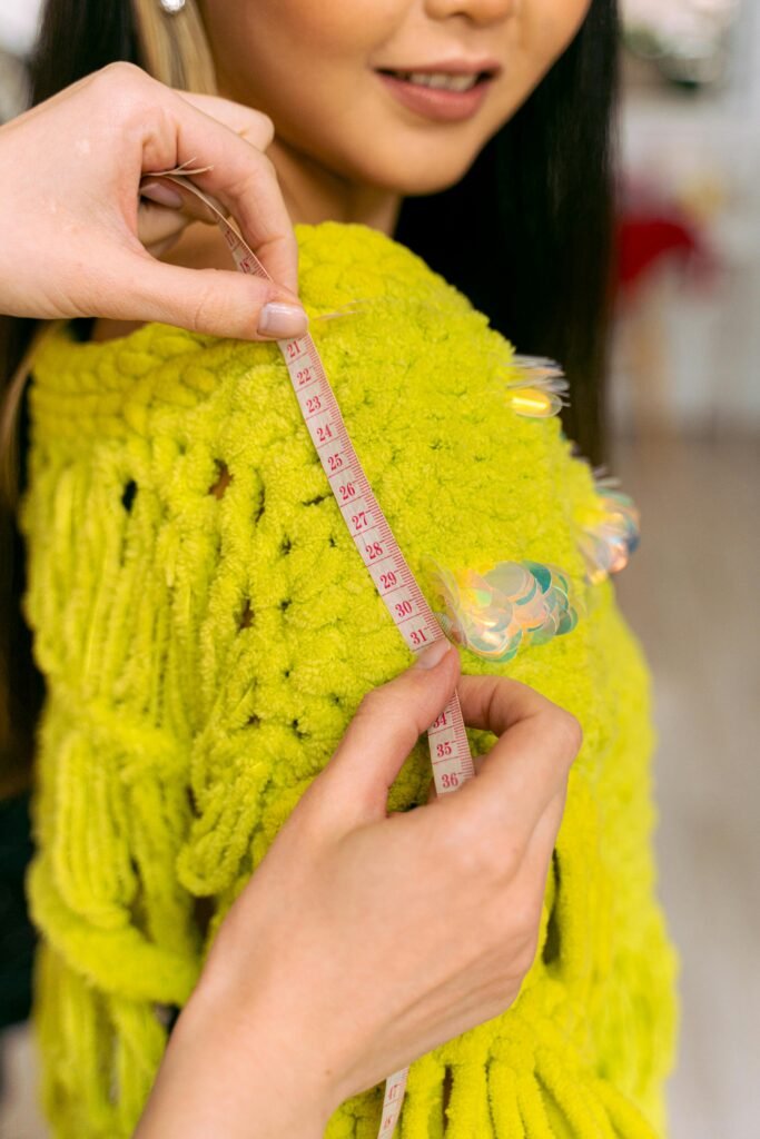Close-up of a person measuring a knitted sweater, showcasing custom fashion design.